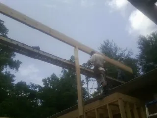 Carpenter setting a ridge beam over a new addition frame — Ice Dam Removal by Roofing Brothers in Eleva